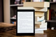 E-Book-Reader vor einem Stapel Bücher